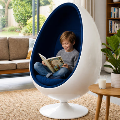 A child sits inside a white egg-shaped pod chair with a deep blue cushioned interior.